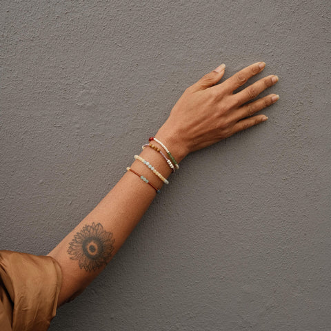 Not I But We's mindfulness bracelets worn by a lady with flower tattoo.