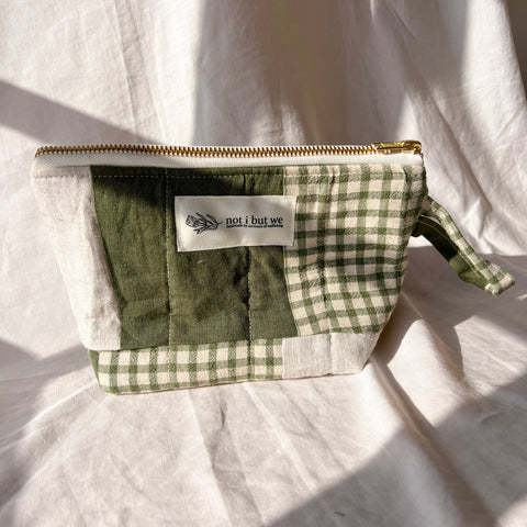 Green checkered pouch with a brand label on a white fabric background