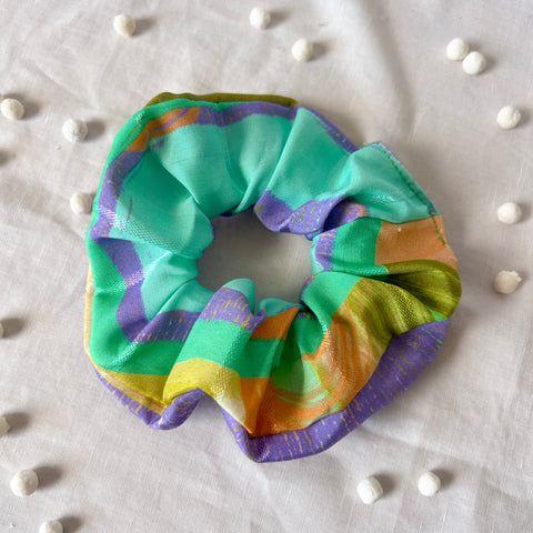 Colorful scrunchie on a light fabric background with small white beads.