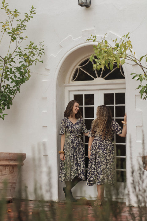 two women wearing the sisterhood dress in a doorway