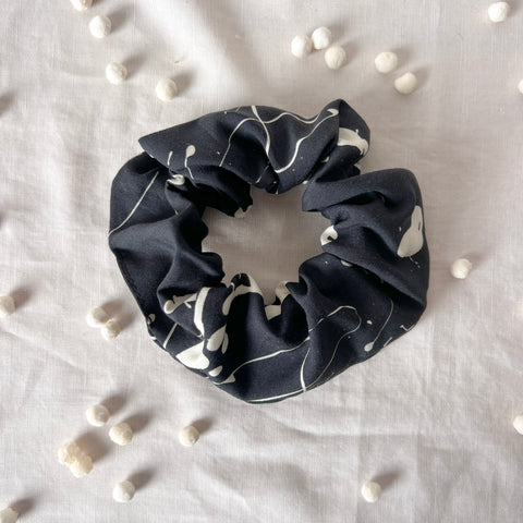 Black scrunchie with white patterns on a light gray background