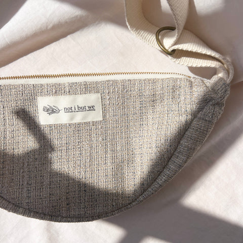 Gray bag with a 'not i but we' label on a light background