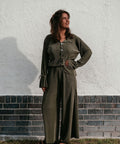 A young woman wearing Not I But We's long sleeve plisse top combined with the matching plisse pants from the aw24 clothing collection.