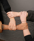 Not I But We's Mindful bracelets worn by different women holding each others wrists.