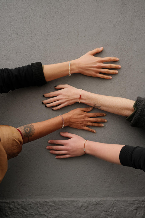 The four mindfulness bracelets with colorful beads worn by different women.