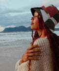 Olive Patchwork Bucket Hat presented by a young woman at the beach.