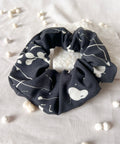 Black scrunchie with white patterns on a light fabric background