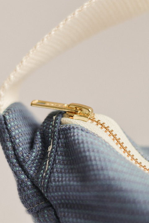Close-up of a blue textured fabric with a gold zipper on a light gray background