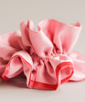 Pink satin hair scrunchie on a light gray background