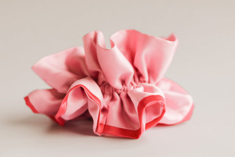 Pink satin hair scrunchie on a light gray background