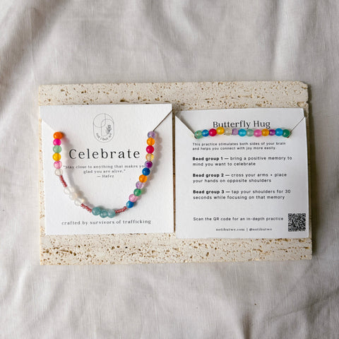 Colorful beaded bracelet on a card with text and QR code on a textured surface