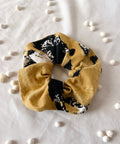 Yellow scrunchie with black and white pattern on a light gray background
