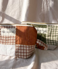 Two patchwork pouches with visible branding on a white fabric background