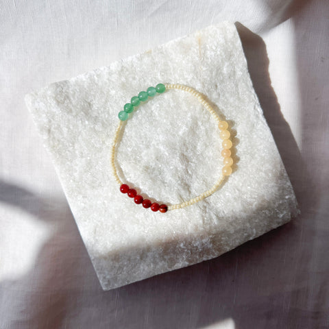 Bracelet with green and red beads on a white stone surface