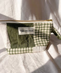 Green checkered pouch with a brand label on a white fabric background