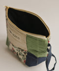 Fabric pouch with floral pattern and green accents on a neutral background