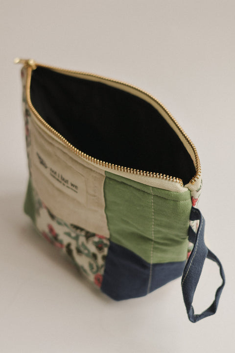 Fabric pouch with floral pattern and green accents on a neutral background