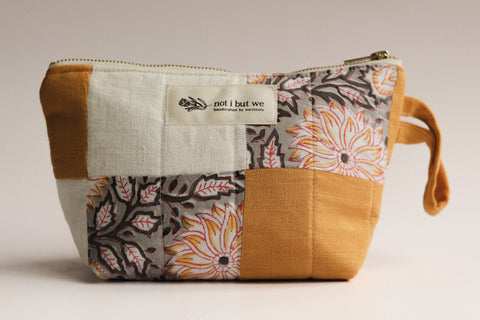 Patchwork pouch with floral patterns and a visible brand label on a neutral background