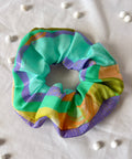 Colorful scrunchie on a light fabric background with small white beads.