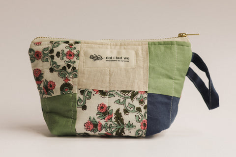 Fabric pouch with floral pattern and visible brand label on a plain background
