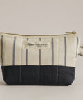Striped fabric pouch with a black bottom section on a beige background