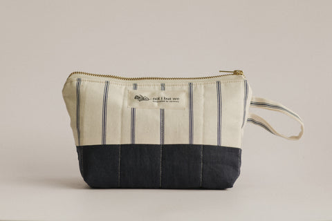 Striped fabric pouch with a black bottom section on a beige background