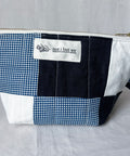 Patchwork pouch with blue and white checkered pattern and 'not i but we' label