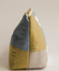 Color-blocked fabric pouch with blue, green and beige sections on a beige background