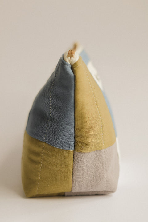Color-blocked fabric pouch with blue, green and beige sections on a beige background
