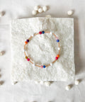 Colorful beaded bracelet on a white textured surface with scattered beads.