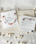 Colorful beaded bracelet with cards on a textured surface
