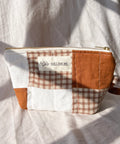 Patchwork pouch with checkered pattern and visible brand label on a light fabric background