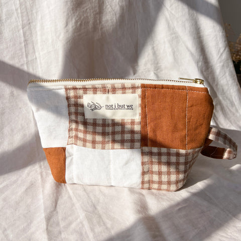 Patchwork pouch with checkered pattern and visible brand label on a light fabric background