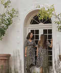 two women wearing the sisterhood dress in a doorway