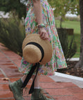 woman wearing sisterhood dress with a hat in her hand