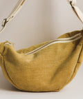 Yellow textured handbag with a white zipper on a beige background