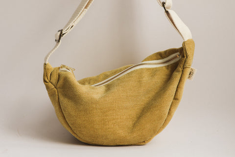 Yellow textured handbag with a white zipper on a beige background