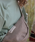 Person wearing a light green ribbed sweater with a gray bag featuring a logo.
