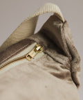 Close-up of a beige fabric with a gold zipper on a neutral background