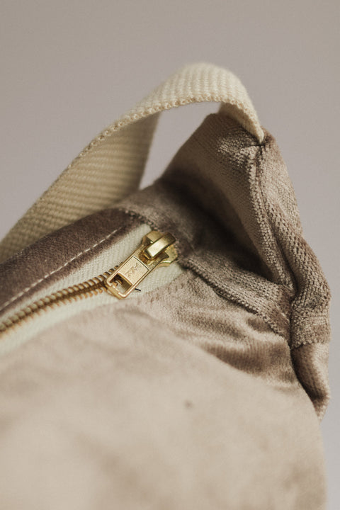 Close-up of a beige fabric with a gold zipper on a neutral background