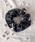 Black scrunchie with white patterns on a light gray background