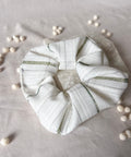White scrunchie with green stripes on a light gray background