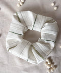 White scrunchie with green stripes on a light gray background